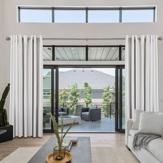 an open living room with white curtains and furniture