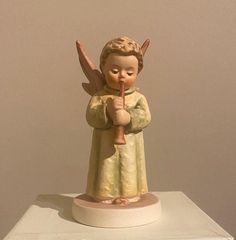 an angel figurine on top of a white box holding a red object in it's hands