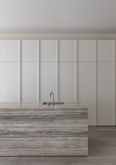 a kitchen with marble counter tops and white cabinets in the back wall, along with a stainless steel faucet