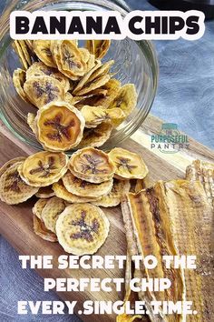 banana chips sitting on top of a wooden cutting board next to a glass bowl filled with bananas