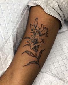 delicate fineline black and grey botanical tattoo of lily plant and flowers Woman Back Of Arm Tattoo, Fine Line Lily Tattoo Design, Lilies Flower Tattoo, Lotus Lily Pad Tattoo, Prairie Lily Tattoo, Bold Line Flower Tattoo, Flowers To Get Tattooed, Botanical Tattoo Sleeve Delicate