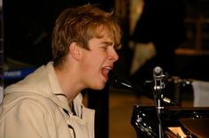 a boy singing into a microphone in front of a piano