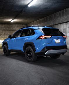 the rear end of a blue toyota rav parked in a parking garage at night