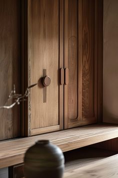 a wooden cabinet with two knobs on the front and back doors, sitting next to a vase