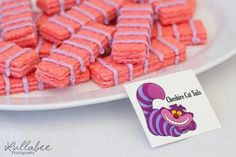 there is a white plate with pink and purple striped cookies on it next to a card