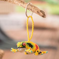 a colorful beaded lizard ornament hanging from a tree branch on a sunny day