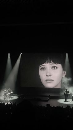 the stage is lit up with three spotlights and two people are standing on it