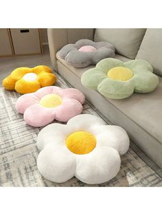 four flower shaped pillows sitting on top of a rug next to a couch and coffee table