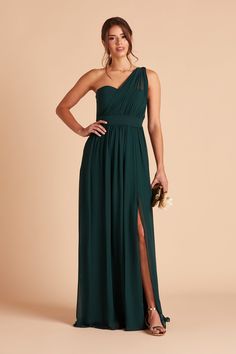 a woman in a long green dress posing for the camera with her hands on her hips