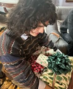 a woman sitting on the floor with presents in her hands