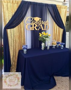 a blue table with yellow and white flowers in vases next to a sign that says congratulations grad