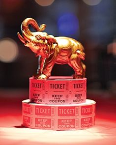 a gold elephant statue sitting on top of three red ticket holders in front of a blurry background