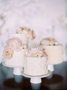 three tiered wedding cakes with pink flowers on each cake stand, sitting on a table