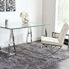 a glass table with two chairs in front of it and a rug on the floor