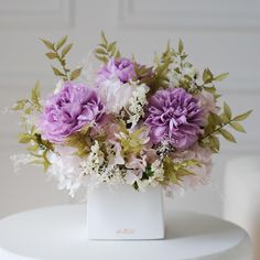 a white vase filled with purple and white flowers