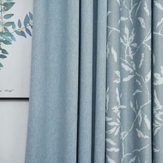 a blue curtain with white leaves on it next to a framed photo and wall hanging