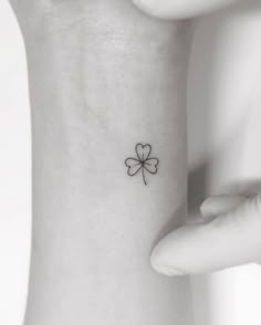 a small four leaf clover tattoo on the left side of the wrist is shown in black and white