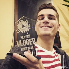 a young man holding an award in front of a sign that says vlogger