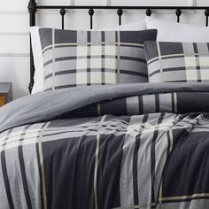 a bed with grey and white plaid sheets