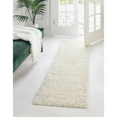 a white rug is on the floor in front of a green couch and door way