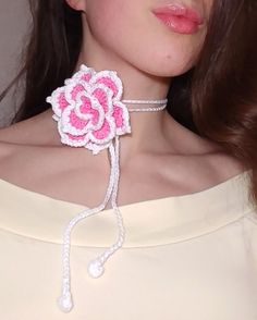 a woman wearing a pink and white crochet flower choker on her neck