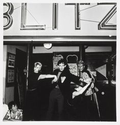 black and white photograph of three women dancing in front of a theater sign that reads, live