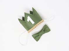 a green felt crown and bow tie on a white background with the word home written across it