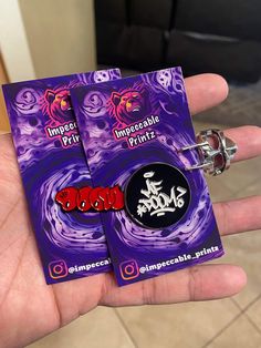 two pin badges in the palm of someone's hand, one is purple and the other is red