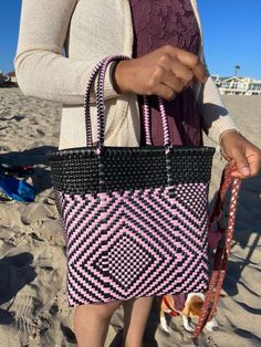 "This beautiful hand-woven, small tote is the latest creation of my business parter Cupertino. Handcrafted in Mexico. 9 1/2\"L x 9 1/2\"H x 5\"D; 16\" H with straps." Summer Pink Woven Leather Bags, Pink Woven Leather Bags For Summer, Rectangular Black Straw Bag With Woven Leather, Black Rectangular Straw Bag With Woven Leather, Pink Rectangular Woven Leather Shoulder Bag, Pink Rectangular Woven Leather Bag, Pink Woven Leather Tote Shoulder Bag, Pink Straw Tote Bag With Leather Handles, Pink Straw Bag With Leather Handles For Shopping