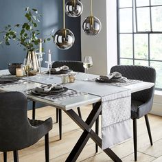 a dining room table is set with place settings and silverware, candles, and vases