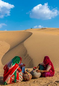 two women sitting in the desert with their bags