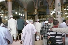 many people are standing in the middle of a room with gold and white decorations on it