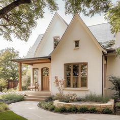 a white house with a large tree in the front yard and steps leading up to it