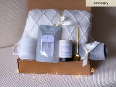 an open box with some items in it on a couch next to a white blanket