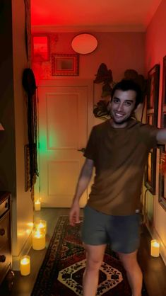 a man standing in a hallway next to a doorway with candles on the floor and walls