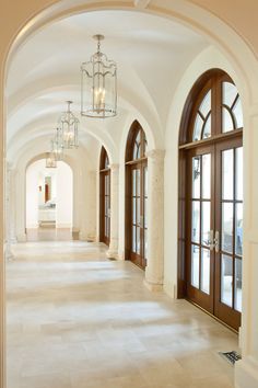 an empty hallway with arched doors and chandeliers