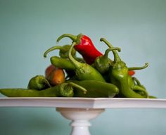 a white plate topped with green peppers on top of a wooden table next to a blue wall