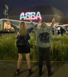 two people standing in front of an arena at night