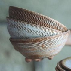 a close up of a stack of wooden bowls on top of each other in front of a person's hand