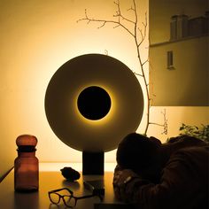 a person sleeping on a table next to a lamp