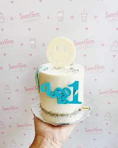 a person holding up a cake with the word glob on it and a smiley face