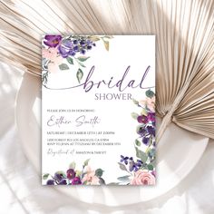 an elegant floral bridal shower card on a plate with palm fronds in the background