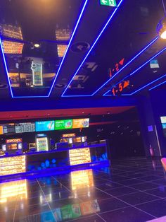 an empty casino room with neon lights and slot machines on the floor in front of them