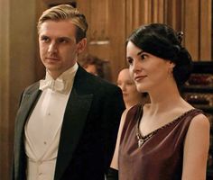 a man in a tuxedo standing next to a woman wearing a dress and bow tie