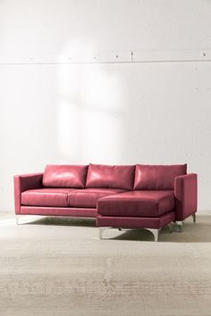 a red leather couch sitting in front of a white wall