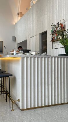 a man sitting at a bar in front of a white wall with vertical lines on it