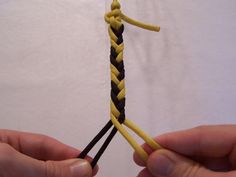 two hands are holding a yellow and black piece of rope that is connected to each other