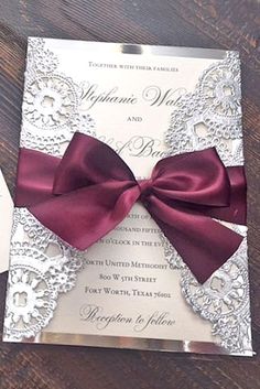 a wedding card with a red bow on the front and white paper in the back