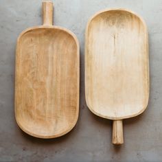 two wooden serving trays sitting next to each other on a cement surface, one holding a spatula