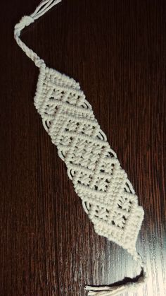 a white crocheted object sitting on top of a wooden table next to a piece of string